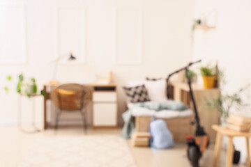 Blurred view of light children's room with bed, study table and kick scooter