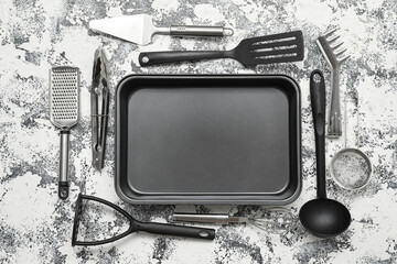 Baking tray with kitchen utensils on white grunge background. Top view