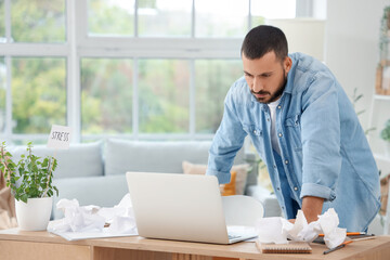 Naklejka na ściany i meble Stressed young man working at home