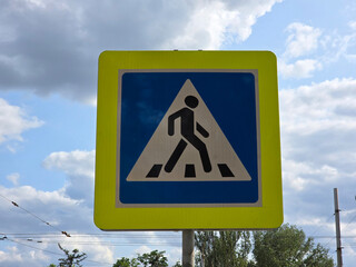 A blue and white pedestrian crossing sign against the sky on a warm summer day. Rules for...