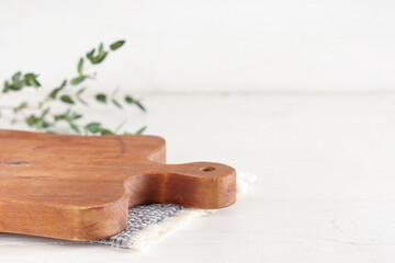 Empty cutting board with napkin and eucalyptus branch on white wooden table, closeup