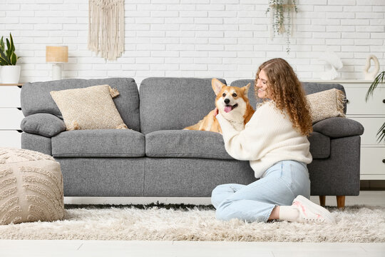 Beautiful young woman with cute Corgi dog in living room