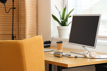 Workplace with computer, headphones and microphone in recording studio