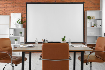 Interior of conference hall with projector screen, shelf units and table