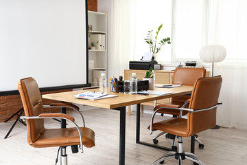 Interior of conference hall with projector screen, shelf unit and table