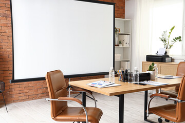 Interior of conference hall with projector screen, shelf unit and table