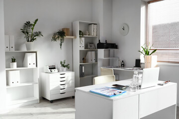 Interior of light office with accountant's desks, shelf units and plants
