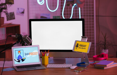 Podcaster's workplace with gadgets and glowing neon lamp in dark studio