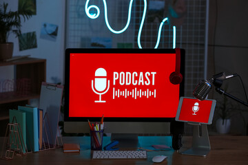 Podcaster's workplace with computer and glowing neon lamp in dark studio