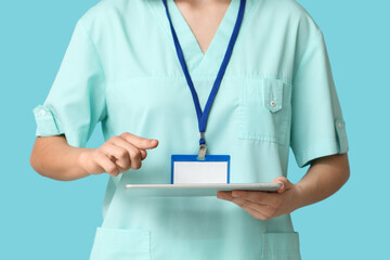 Female cardiologist with badge and tablet on blue background, closeup