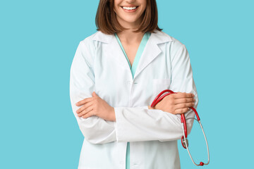 Happy female cardiologist with stethoscope on blue background, closeup