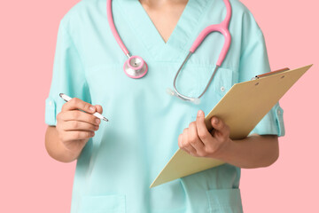 Female cardiologist with stethoscope and clipboard on pink background, closeup