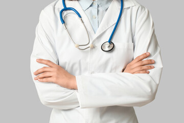 Female cardiologist with stethoscope on grey background, closeup