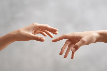 close-up of hands reaching towards each other fingers almost touching with neutral background for minimalistic look