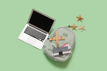 Blank laptop with travel accessories and starfishes on green background