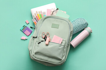 Stylish school backpack with different stationery supplies and water bottle on turquoise background
