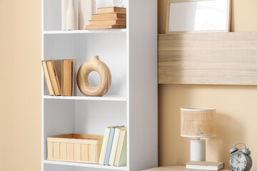 Bookshelf with decor near beige wall in room
