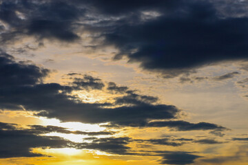 The evening sky, covered with dark clouds, through which golden sunbeams break through. This creates a dramatic and powerful landscape reflecting the force of nature.