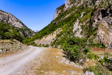 A dirt winding road between mountains. Albanian Alps, also known as the Accursed Mountains, Valbone...