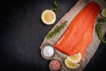 Salmon. Fresh raw salmon fish fillet with cooking ingredients on dark background, top view. High...