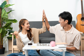 Financial empowerment and teamwork. Young couple high-fiving after budgeting session at home.