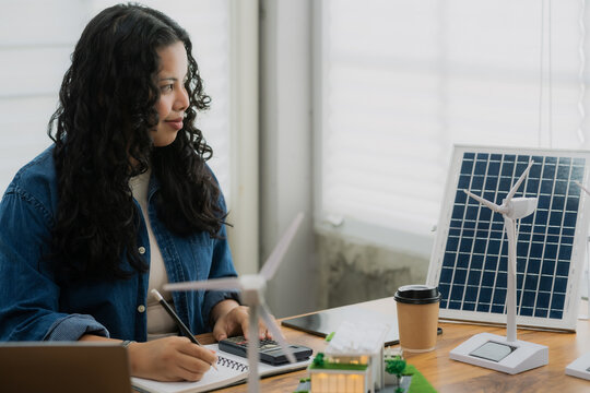 A female engineer uses a calculator for financial or technical calculations for a renewable energy project with wind turbines