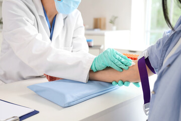 Female doctor disinfecting donor's arm before blood transfusion in clinic