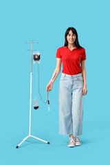 Young woman donating blood on blue background