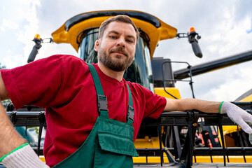 Low angle portrait of farm machinery operator by combine harvester