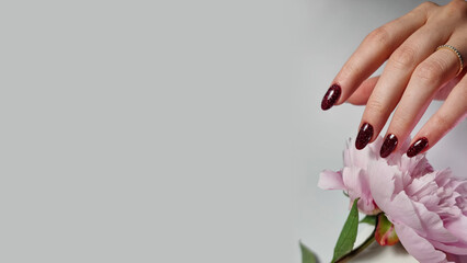A close-up of a hand with a neat  manicure on nails, set against a white background with pink flower. Creating a clean and elegant look. Ideal for themes related to beauty, nail care, manicure, cosmet