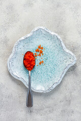 a spoon with orange flying fish caviar, Tobiko, on a light blue plate, caviar for rolls and sushi, close-up,