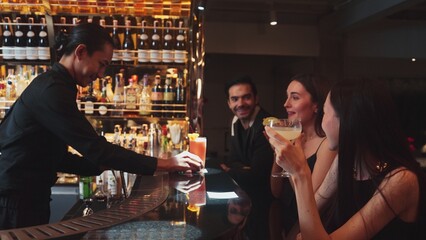 Bartender serving Margarita cocktail savoring sour tasty drink to woman customer drinking with couple or group friend at luxurious bar creating happiness moment meeting at vibrant nightclub. Vinosity.