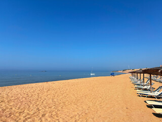 Obraz premium beautiful golden sand beach with white sunbeds and blue sea and skies in the background