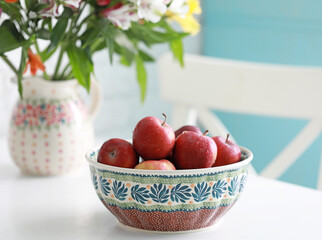Beautiful ceramic brown bowl with fresh red apples on the white table. Selective focus.
