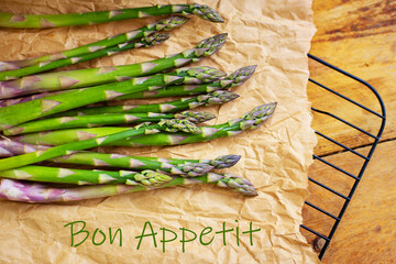 Fresh green asparagus spears arranged on crumpled brown paper, ready for cooking. Bon appetit