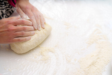Hands kneading dough on a floured surface in a bright kitchen during the afternoon