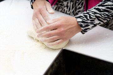Hands kneading dough on a marble counter in a kitchen, demonstrating traditional baking techniques effectively