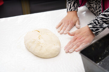 Hands kneading dough on a clean countertop in a home kitchen during a culinary session