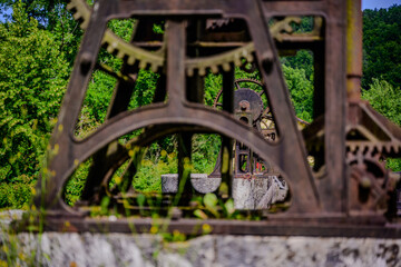 Old industrial machinery surrounded by greenery in a natural setting with historical significance