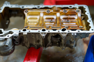 Engine oil pan undergoing cleaning and inspection in an automotive workshop during the afternoon