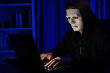White criminal anonymous mask installing coding password encryption by programming hack, trying to make insecure thorough privacy taking massive database on computer for ransom to company. Pecuniary.