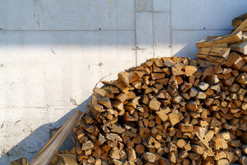 Stacked firewood against a weathered concrete wall in soft afternoon sunlight
