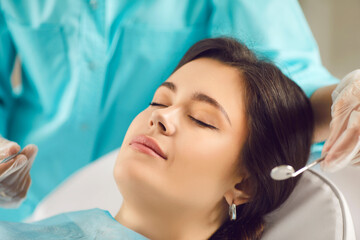 Beautiful young woman closed her eyes in the dentists chair, close-up of her face. Concept of...