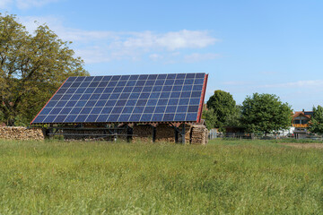 Solar panels installed on a barn roof in a rural landscape under a clear blue sky