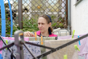 Woman hanging laundry on a clothesline in a garden during a sunny afternoon in a residential area