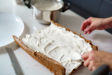 Baking a creamy dessert at home with a focus on spreading frosting on freshly baked cake