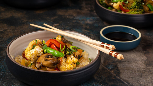 Bowl of Asian Fried Rice with Vegetables and Seafood on Dark Rustic Table