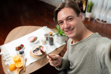 Smiling smart influencer making take photo selfie with healthy food yogurt toppings with berry fruit background, promoting with advertisement online for benefit of vitamin and fiber meal. Pecuniary.