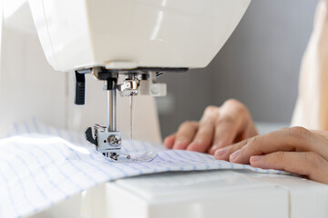 woman sews a light fabric on a sewing machine. making clothes, hobbies. a sewing studio, a clothing designer, a tailor sews on a household sewing machine.