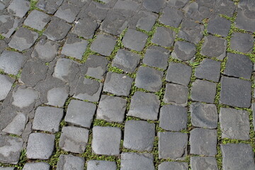 An old stoneblock pavement cobbled with natural stone blocks of different colors. Paving stone pavement texture. Cobblestone pavement top view. Old stone sidewalk. Paving texture. Cobble stone road